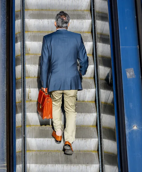 Деловой человек едет на эскалаторе, чтобы добраться до работы — стоковое фото