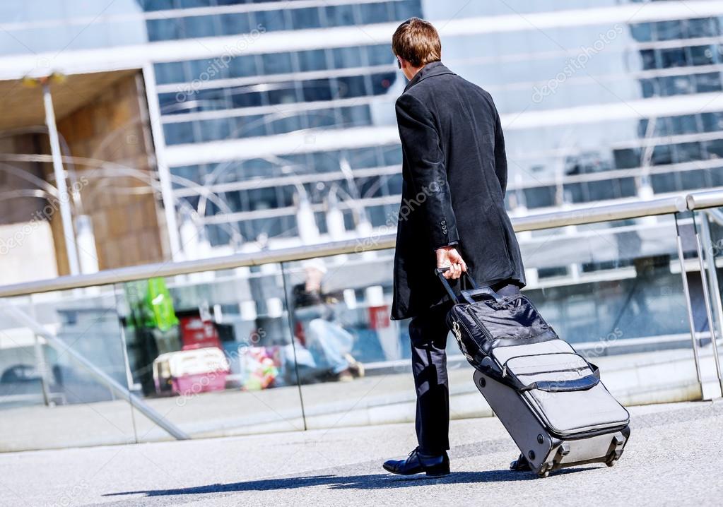 Business man walking with suitcase in the street