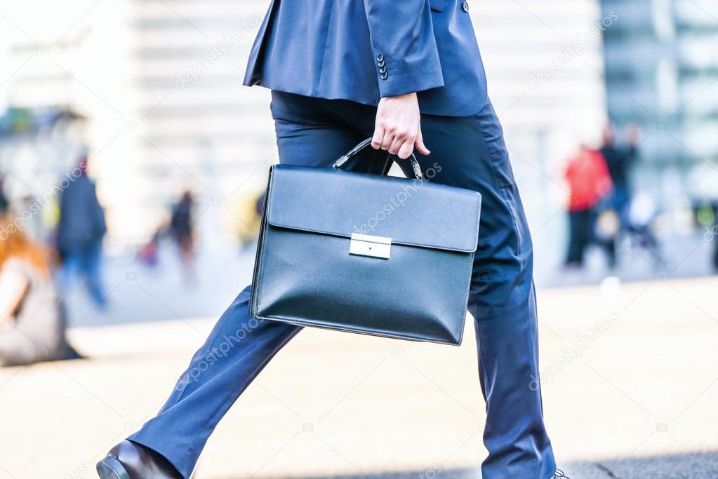 Business man walking with suitcase in the street