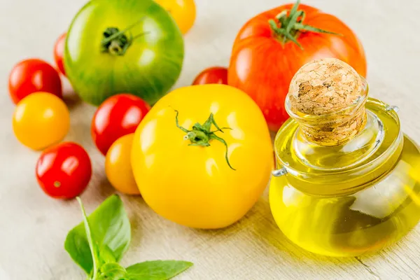 Varieties of colorful tomatos and olive oil — Stock Photo, Image
