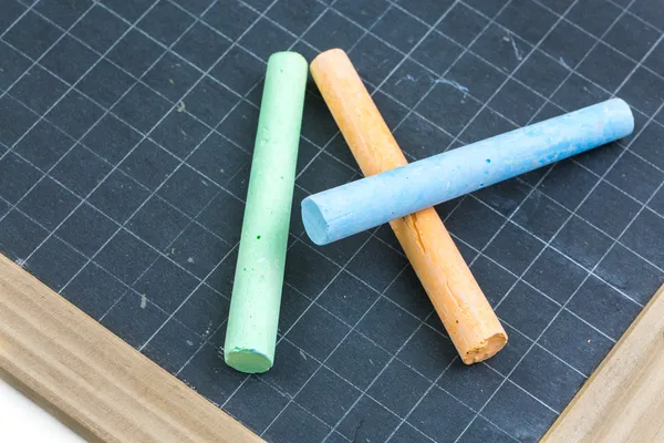 Colored chalk placed on a school slate — Stock Photo, Image