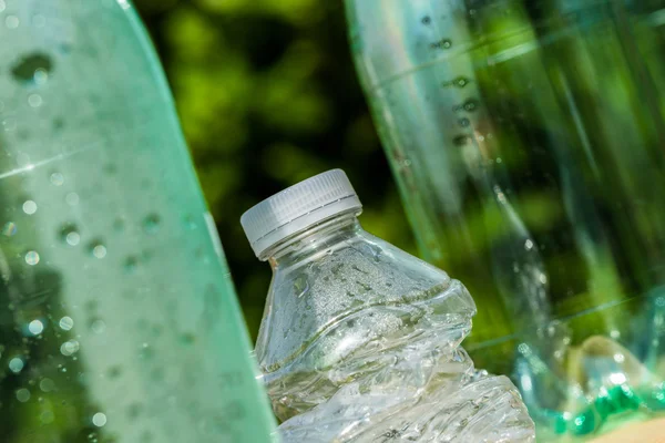 Tre bottiglie di plastica con una bottiglia schiacciata — Foto Stock
