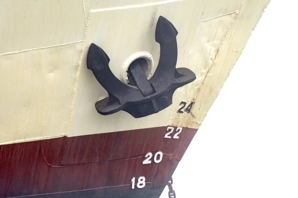 Old ship bow, anchor tied to the hull of a ship moored in a harbor.