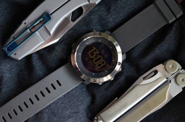 Saat, çakı ve gri arka planda çoklu alet. İş için bir takım erkek aksesuarları. Moda ve seyahat konsepti.