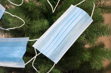 Protective face masks on the Christmas tree. Quarantine, banning public events for people during the covid-19 epidemic. Stay home.