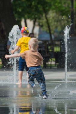 Mykolaiv, Ukrayna - 29 Mayıs 2021: Mutlu çocuklar bir şehir parkında çeşme içinde yıkanır. Çocukluk ve çocuk bakımı. Uluslararası Çocuk Günü.