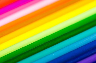 Gökkuşağı çok renkli deseni. Renkli kalemleri yakın çekimde dolduruyor. Bulanık ve odaklanmış arkaplan.