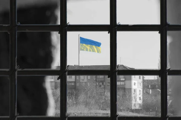 Mavi gökyüzündeki Ukrayna bayrağındaki hapishane parmaklıklarından bak. Rusya 'nın Ukrayna' ya saldırması. Savaştan sonra özgürlük ve barış kavramı. Özel olarak odaklanmış fotoğraf.