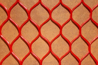 Kahverengi arka planda uzuvlar şeklinde soyut tekrarlayan desenleri olan kırmızı plastik bir ağın kusursuz dokusu. Doğulu desen.