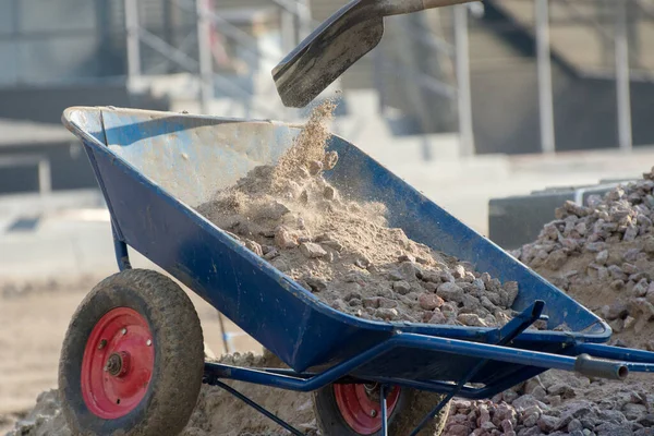 Arbetaren Byggarbetsplatsen Lastar Gruset Med Spade Skottkärran Bild Med Damm — Stockfoto