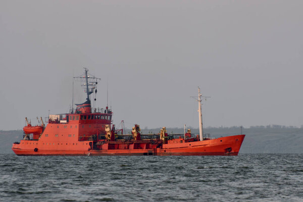 The red ship floats on the waves in the sea.