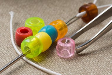 İğneli renkli boncuklar, yakın çekim, makro. Boncuklardan çocuk kolyesi yapmak. Ev yapımı boncuk..