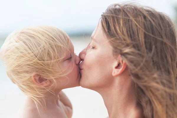 Matka a malá dcera líbání na pláži — Stock fotografie
