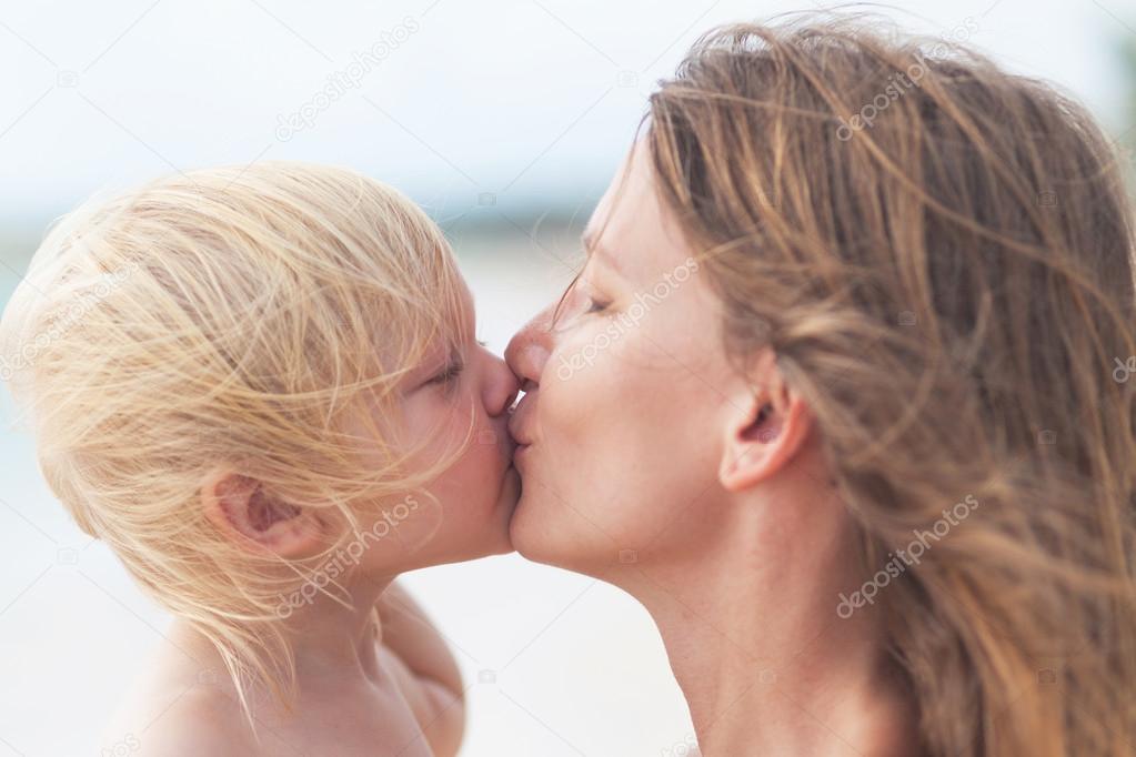 Mother and little daughter kissing on the beach