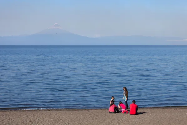 Chilean family at the lake in the city Frutillar on the background of the volcano Osorno — Stock Photo, Image