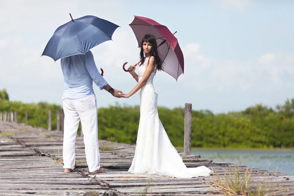 Wedding couple on the bridge with umbrellas — Stock Photo, Image