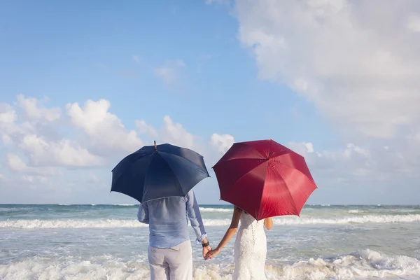 Pareja recién casada en la playa con sombrillas —  Fotos de Stock