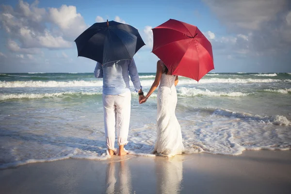 Couple of newly married on the beach with umbrellas — Stock Photo, Image