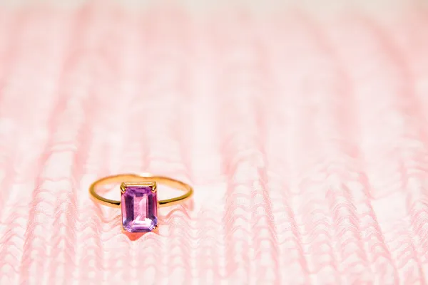 Gold ring with amethyst on rosy chiffon — Stock Photo, Image