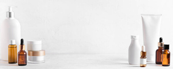 Косметические средства для кожи на белом столе, ассортимент косметических бутылок, здоровая косметология, концепция санаторно-курортного лечения, копировальное пространство.
