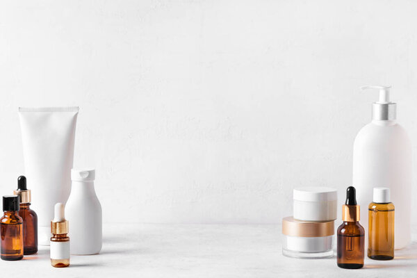 Косметические средства для кожи на белом столе, ассортимент косметических бутылок, здоровая косметология, концепция санаторно-курортного лечения, копировальное пространство.
