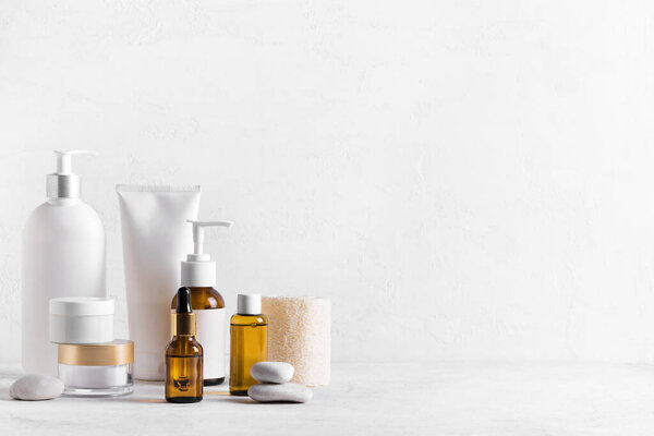 Косметические средства для кожи на белом столе, ассортимент косметических бутылок, здоровая косметология, концепция санаторно-курортного лечения, копировальное пространство.