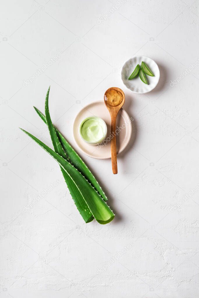 Aloe vera plant leaves, gel, skin care products on white, top view, copy space. Natural organic aloe vera cosmetics for face and body care.