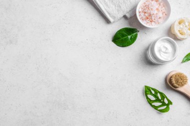 Beyaz taş zemin, yeşil yapraklar, deniz tuzu, kozmetik kremi, havlu ve masaj fırçası, üst görünüm, kopyalama alanı üzerine kaplıca ve cilt bakımı kavramı.