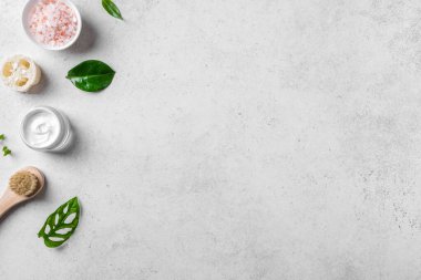 Beyaz taş zemin, yeşil yapraklar, deniz tuzu, kozmetik krem ve masaj fırçası, üst görünüm, kopyalama alanı üzerine kaplıca ve cilt bakımı kavramı.