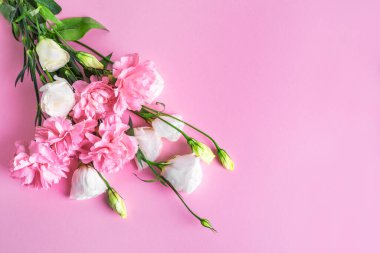 Pembe karanfil ve pembe pastel arka planda beyaz Eustoma çiçekleri kompozisyonu, yaratıcı düz döşeme, kopyalama alanı. Bahçe çiçekleri, bahar yazı kızarık çiçek tasarımı, anneler günü konsepti..