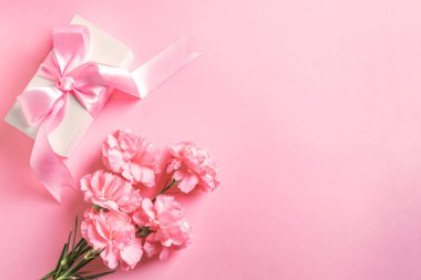 Anneler Günü, Kadınlar Günü, Sevgililer Günü tasarım konsepti, güzel pembe karanfil çiçekleri ve pastel arka planda hediye kutusu, üst manzara, düz alan, fotokopi alanı..