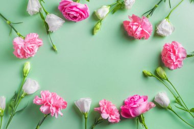 Pembe gül, şakayık ve karanfilli çiçek çerçevesi yeşil pastel arka plan, yaratıcı düz döşeme, kopyalama alanı. Bahçe gülleri, ilkbahar yazı çiçek tasarımı konsepti.