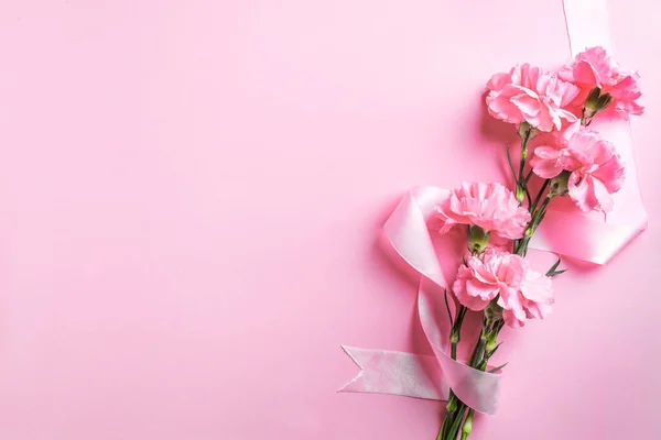 Розовые Гвоздичные Цветы Лента Розовом Пастельном Фоне Скопировать Пространство День — стоковое фото