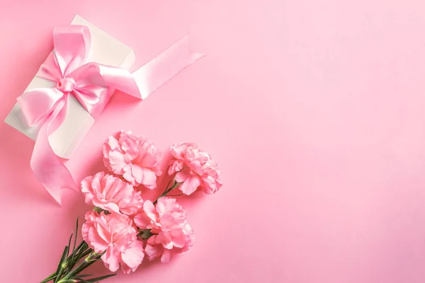 母の日 女性の日 バレンタインデーのデザインコンセプト 美しいピンクのカーネーションの花とギフトボックスパステルピンクの背景 トップビュー フラットレイアウト コピースペース — ストック写真