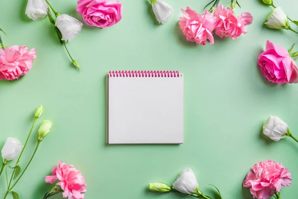 白色的花朵和空白的便笺框架在绿色的粉刷背景上 创意扁平 复制空间 花园玫瑰 牡丹和康乃馨 春夏红花设计理念 — 图库照片