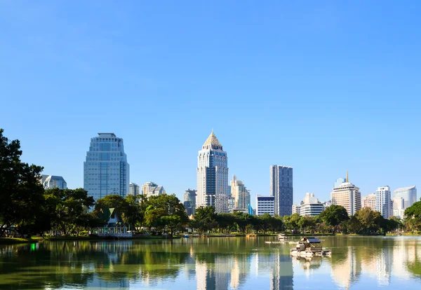 A paisagem urbana de distrito de negócios de um parque com céu azul — Fotografia de Stock