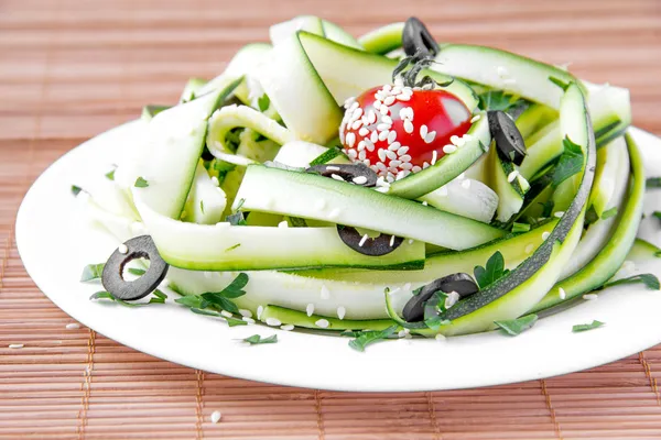 Salad from the zucchini ribbons, tomato and black olive — Stock Photo, Image