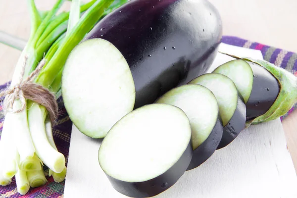 Vers gesneden aubergine en een heleboel groene lente-uitjes — Stockfoto