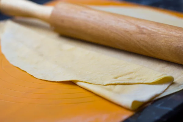 Thin dough for pasta or pizza on table with rolling pin — Stock Photo, Image