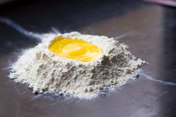 Горная мука с углублением и яйцом, приготовление домашней пасты — стоковое фото