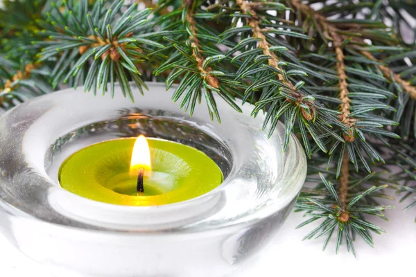 Green candle with flame and branch of Christmas tree — Stock Photo, Image