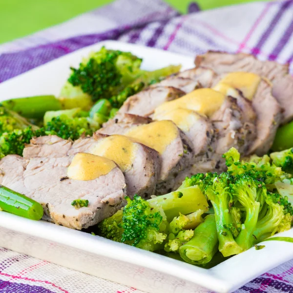 Запечене, нарізане філе свинини з зеленими овочами, брокколі та — стокове фото