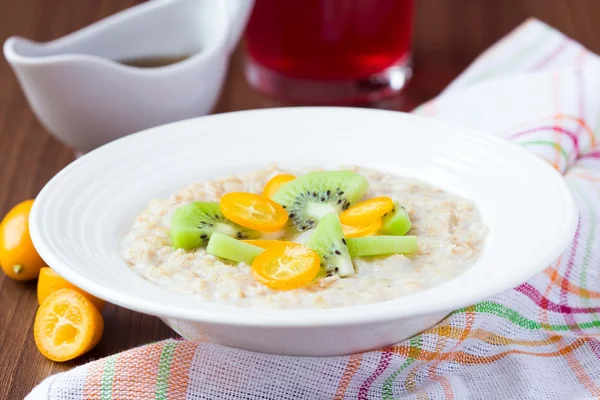 Oat porridge with fruit, orange, cumquat, kiwi, maple syrup, del — Stock Photo, Image