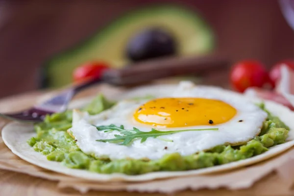 Breakfast with fried egg and sauce of avocado on grilled flour t