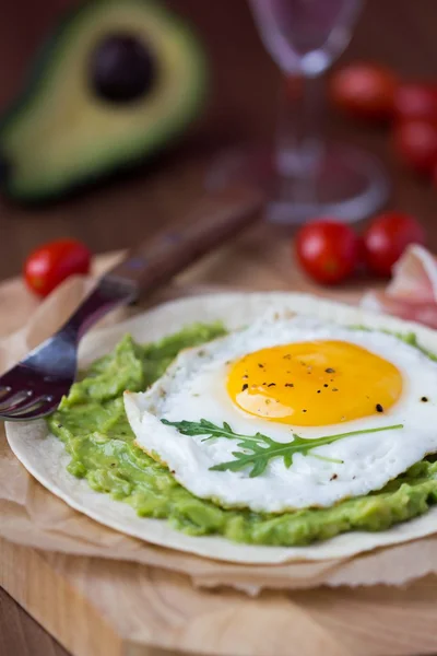 Сніданок зі смаженим яйцем та соусом авокадо на смаженому борошні т — стокове фото