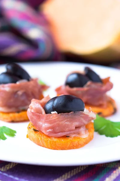 Canape appetizer of pumpkin, jamon ham, black olives, cheese, go — Stock Photo, Image