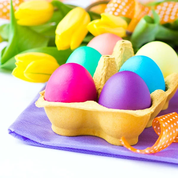 Colorful easter eggs in packing box with tulips flowers — Stock Photo, Image