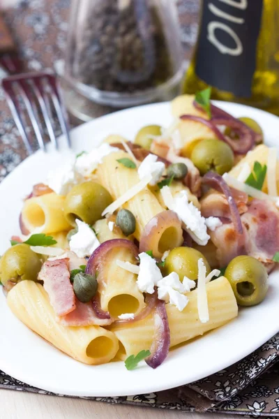 Rigatoni pasta met spek, rode ui, groene olijven, fetakaas, — Stockfoto