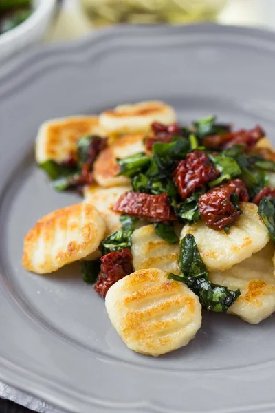 Stekt potatis gnocchi med sås på soltorkade tomater, spenat, ital — Stockfoto