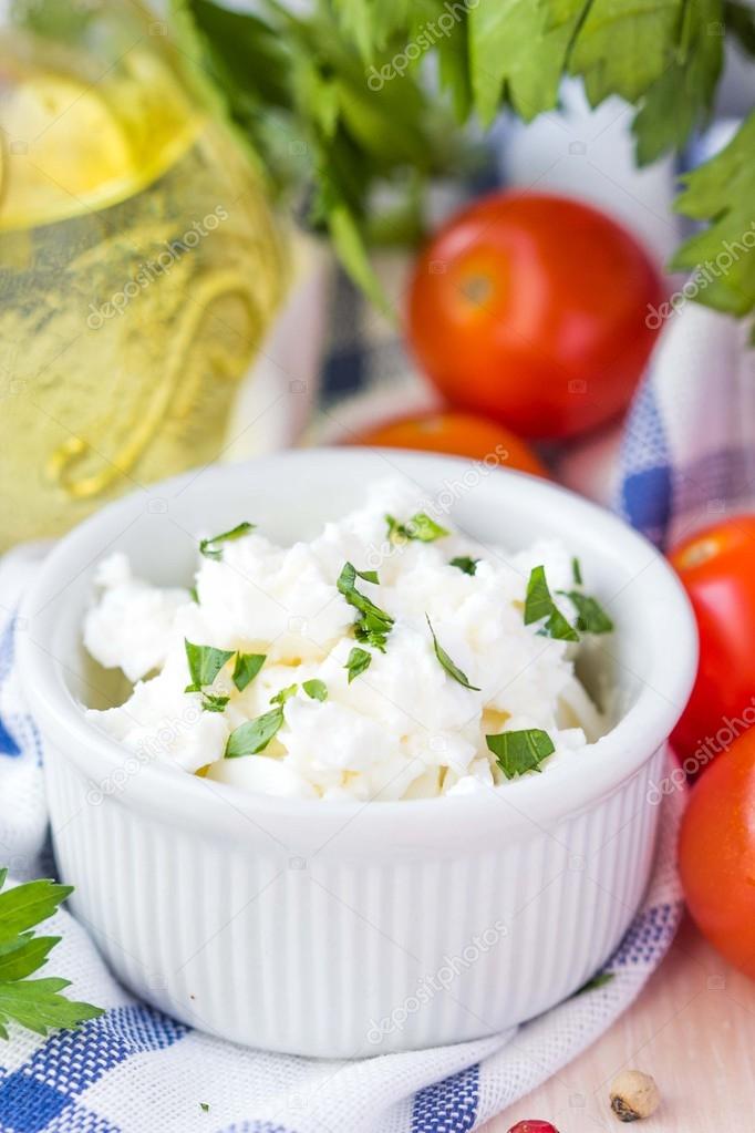 White soft cheese, feta, goat in bowl with tomatoes, parsley, ol